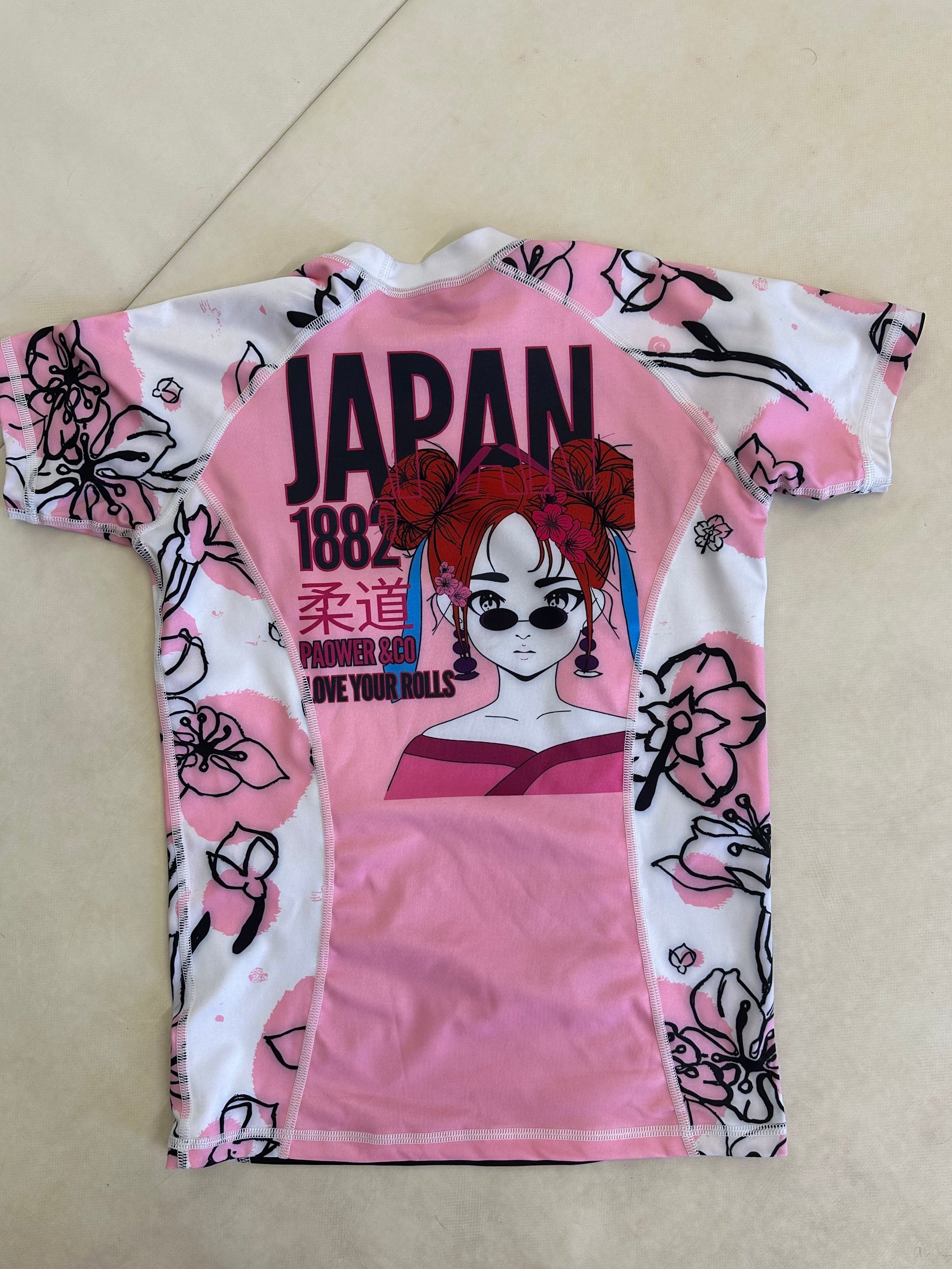 Pink and white garment with black floral patterns and 'Japan' text on a beige surface.