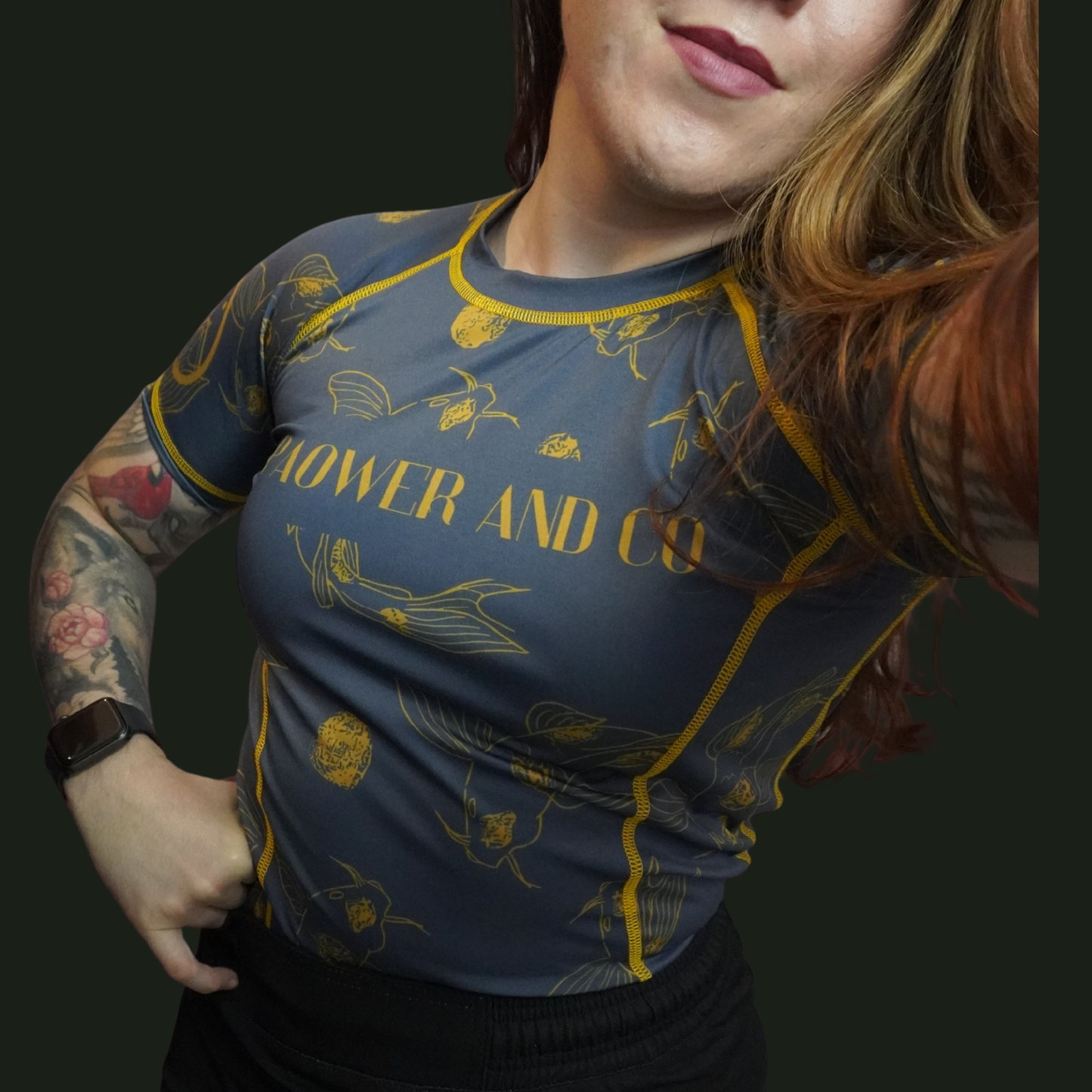 Person wearing a blue and yellow patterned rashguard  with 'Paower and co" logo on the front. 